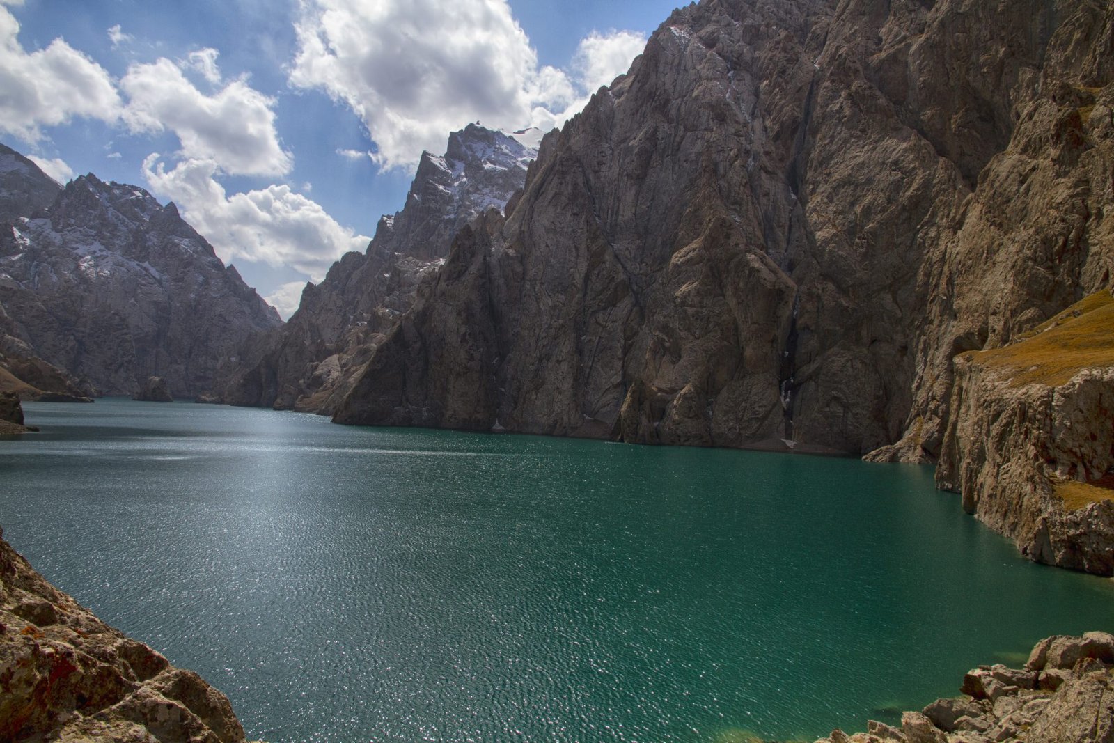 Kel-Suu lake beneath sheer rock walls in Naryn province, Kyrgyzstan